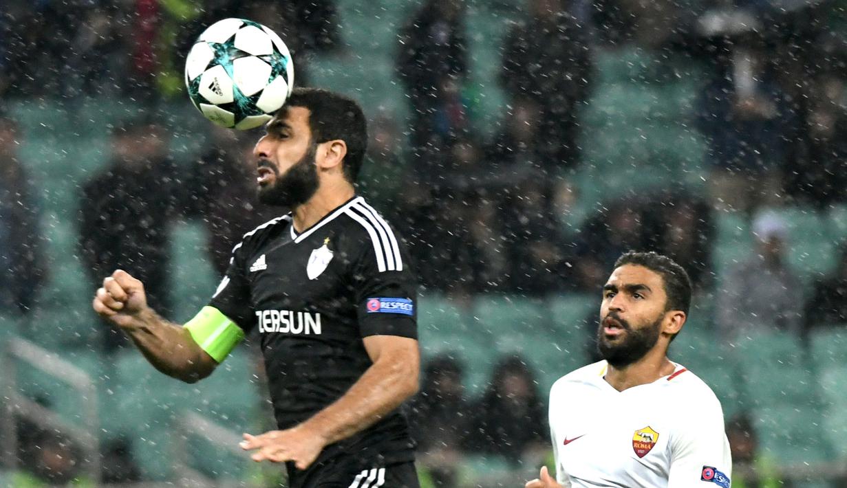 Kapten Qarabag FK, Rashad Sadygov  (kiri) menghalau bola dari kejaran pemain pemain AS Roma, Gregoire Defrel pada laga grup C Liga Champions di Baki Olimpiya Stadionu, Baku, (27/9/2017). AS Roma menang 2-1. (AFP/Vano Shlamov)