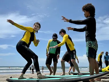 Orang-orang belajar berselancar di pantai Kuta, Bali, 8 Desember 2023. (SONNY TUMBELAKA/AFP)