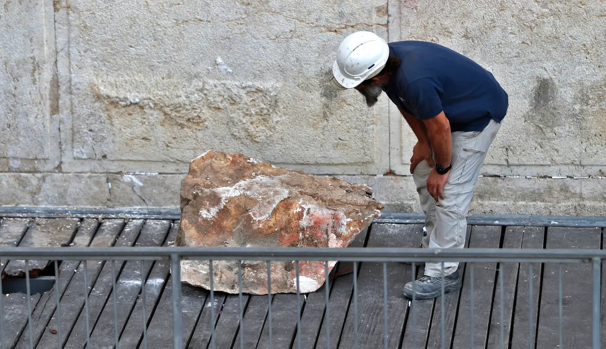 Pekerja Otoritas Pengurus Benda Antik Israel memeriksa batu besar yang jatuh dari Tembok Ratapan di Kota Tua Yerusalem, Rabu (25/7). Rabbi Tembok Ratapan menyebut kejadian ini langka dan belum pernah muncul dalam berpuluh-puluh tahun. (AFP/AHMAD GHARABLI)