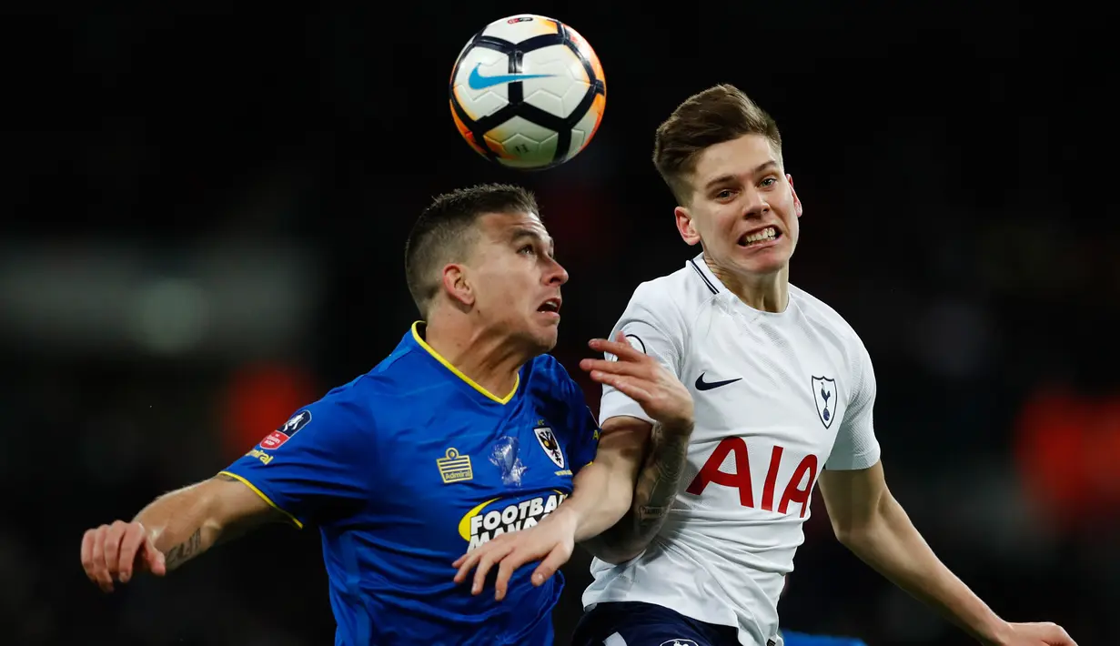 Pemain Tottenham Hotspur, Juan Foyth berebut bola dengan striker Wimbledon Cody McDonald pada pertandingan putaran ketiga FA Cup di Stadion Wembley, Minggu (7/1). Tottenham Hotspur lolos ke babak keempat Piala FA usai menang telak 3-0. (Adrian DENNIS/AFP)