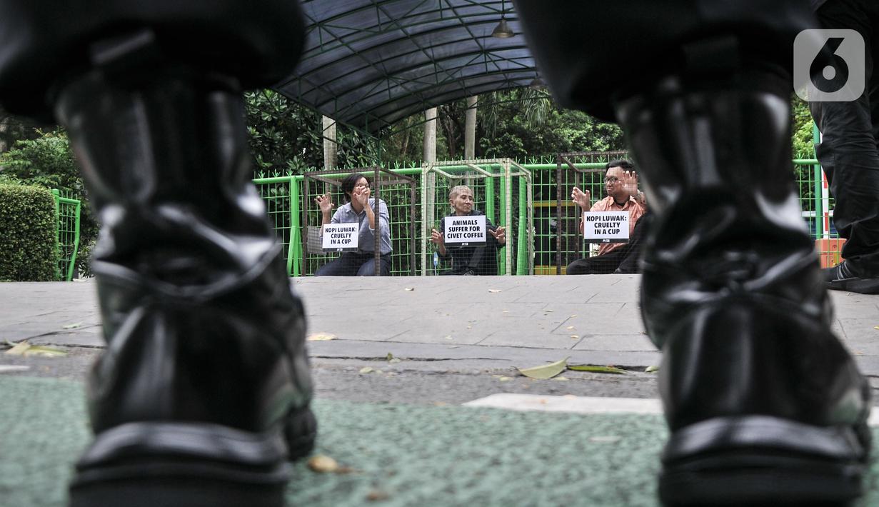 Aktivis People for the Ethical Treatment of Animals (PETA) mengurung diri di dalam kandang saat aksi teatrikal mengecam eksploitasi luwak untuk kepentingan produksi kopi di depan Kantor Kementerian Lingkungan Hidup dan Kehutanan (KLHK), Jakarta, Rabu (25/1/2023). Aktivis PETA mengurung diri di dalam kandang sebagai bentuk protes dan mendesak pihak berwenang melarang peternakan luwak untuk kepentingan produksi kopi. (merdeka.com/Iqbal S Nugroho)