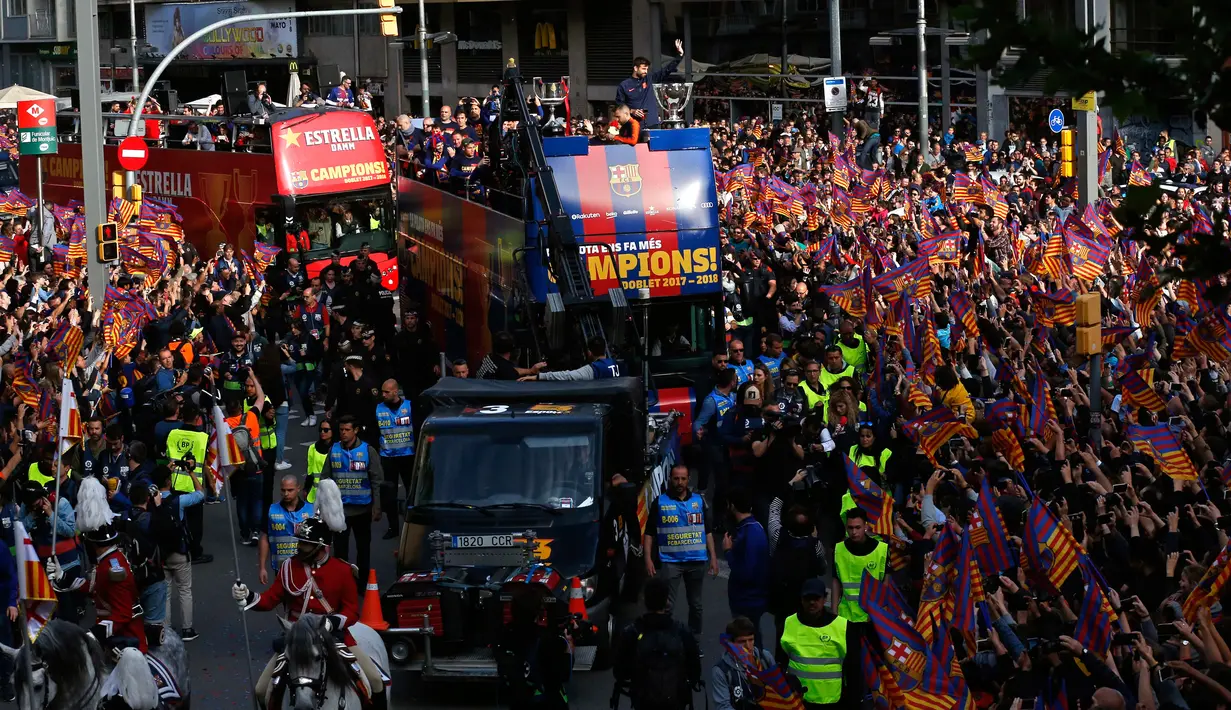 Para pemain Barcelona berada di atas bus saat melakukan parade u di Barcelona (30/4). Dengan bus atap terbuka, Lionel Messi dan kawan-kawan memamerkan Piala Liga Spayol dan juga Piala Copa del Rey. (AP/Manu Fernandez)