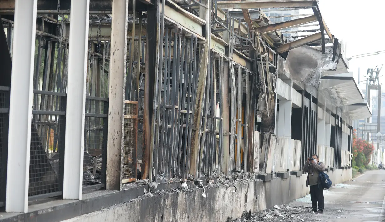 Pewarta foto mengambil gambar halte transjakarta yang dibakar massa perusuh di Kawasan Bundaran HI Jakarta, Jumat (9/10/2020). Demo menolak omnibus law Undang-Undang (UU) Cipta Kerja diwarnai kericuhan dan pembakaran terhadap sejumlah halte Transjakarta. (merdeka.com/Dwi Narwoko)