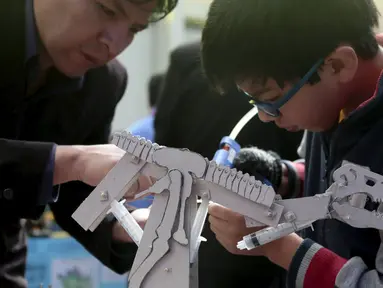 Seorang anak sedang mereparasi robotnya pada olimpiade sains di La Paz , Bolivia,  Senin (10/8/2015). 150 robot dipamerkan disini dan dipilih siapa yang terbaik. (REUTERS/David Mercado)