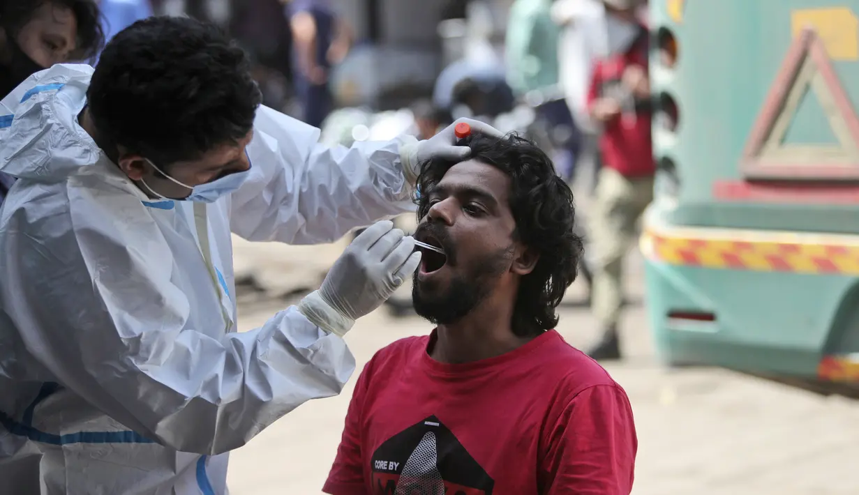 Seorang petugas kesehatan mengumpulkan sampel swab penumpang untuk diuji COVID-19 di sebuah terminal bus di Jammu, India (26/3/2021). India sejauh ini melaporkan lebih dari 11,5 juta kasus infeksi virus Corona, total tertinggi ketiga di dunia setelah Amerika Serikat dan Brasil. (AP Photo/Channi Anan