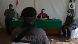 Pelanggar mengikuti sidang di tempat saat Operasi Yustisi di Kawasan Danau Sunter, Jakarta, Rabu (16/9/2020). Warga yang melanggar protokol Covid-19 langsung disidang tindak pidana ringan (tipiring) di tempat dengan membayar denda Rp 55.000 maupun sanksi sosial. (merdeka.com/Imam Buhori)
