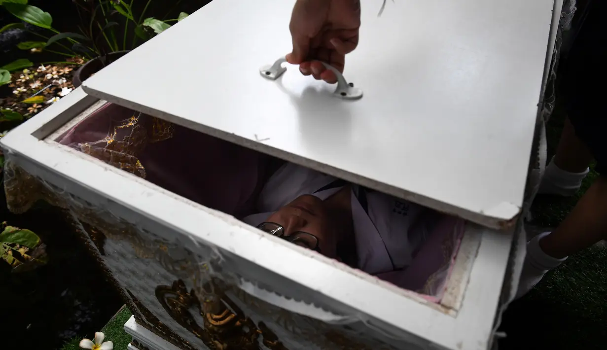 Seorang siswa remaja berbaring di dalam peti mati di Kid Mai Death Awareness Cafe, Thailand (30/3). Selain itu cafe ini juga menyediakan menu yang cukup aneh seperti minuman rasa "kematian" dan "menyakitkan". (AFP/Lillian Suwanrumpha)