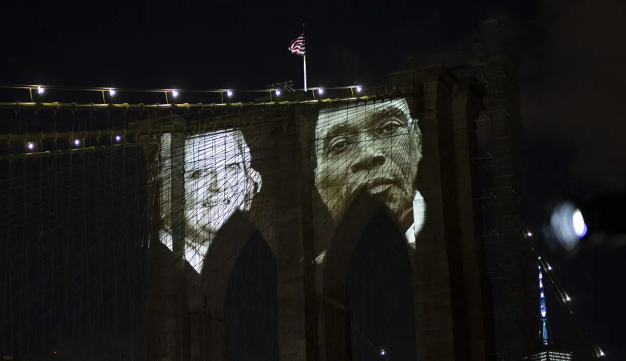 Gambar korban diproyeksikan pada Jembatan Brooklyn saat Hari Peringatan COVID-19 di Brooklyn, New York, Amerika Serikat, 14 Maret 2021. Ada sejumlah pidato yang disampaikan oleh para pemuka agama dalam acara ini. (Kena Betancur/AFP)