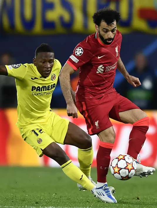 <p>Bek Villarreal Pervis Estupinan berebut bola dengan penyerang Liverpool Mohamed Salah pada leg kedua semifinal Liga Champions di Estadio de la Ceramica atau El Madrigal, Rabu (4/5/2022) dini hari WIB. Liverpool lolos ke final usai hampir kena comeback sebelum menang 3-2. (AP Photo/Alberto Saiz)</p>