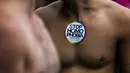 Seorang pria berpose dengan stiker ‘Stop Homophobia’ menempel di dadanya saat parade ‘Gay Pride’ di Berlin, Jerman, Sabtu (22/7). Sebanyak 393 anggota parlemen Jerman menyetujui pernikahan sesama jenis. (AP/Markus Schreiber)