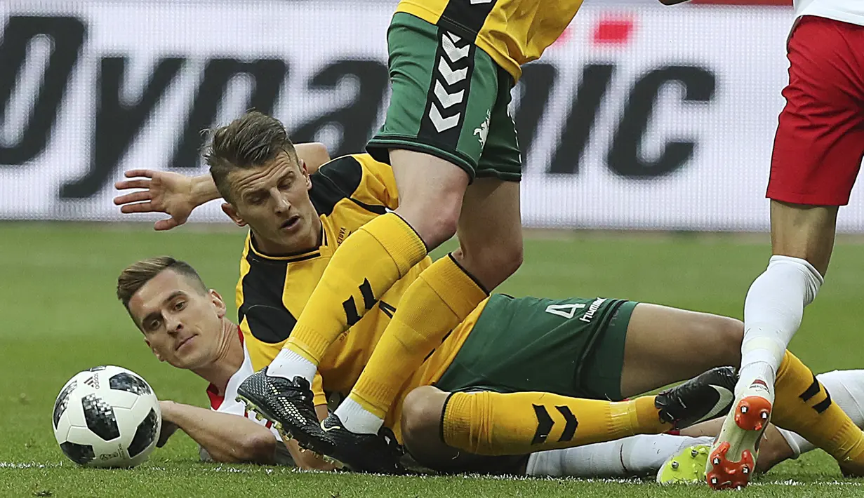 Pemain Polandia, Arkadiusz Milik (kiri) jatuh saat berebut bola dengan pemain Lituania, Modestas Vorobiovas pada laga uji coba di Stadion Narodowy, Warsaw, Polandia, (12/6/2018). Polandia menang 4-0. (AP/Czarek Sokolowski)