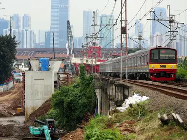 Kereta melintas di dekat pembangunan proyek double-double track (DDT) Paket A Manggarai-Jatinegara, Jakarta (3/3). Proses pengerjaan Paket A jalur Manggarai-Jatinegara terus di kebut sehingga ditargetkan selesai tahun 2019. (Liputan6.com/Johan Tallo)