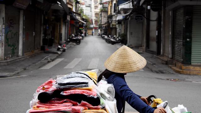 Seorang penjual berjalan melewati jalan sepi di tengah kekhawatiran tentang penyebaran Virus Corona COVID-19 di Hanoi Vietnam pada 26 Maret 2020. (Nhac Nguyen / AFP)