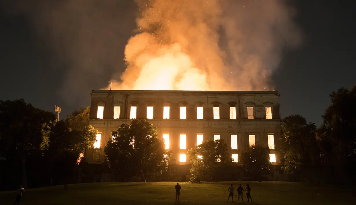 Warga menyaksikan kebakaran yang melanda Museum Nasional Brasil berusia 200 tahun di Rio de Janeiro, Minggu (2/9). Museum itu didirikan pada 1818 oleh Raja Joao VI dan merupakan salah satu museum terpenting di Brasil. (AP/Leo Correa)