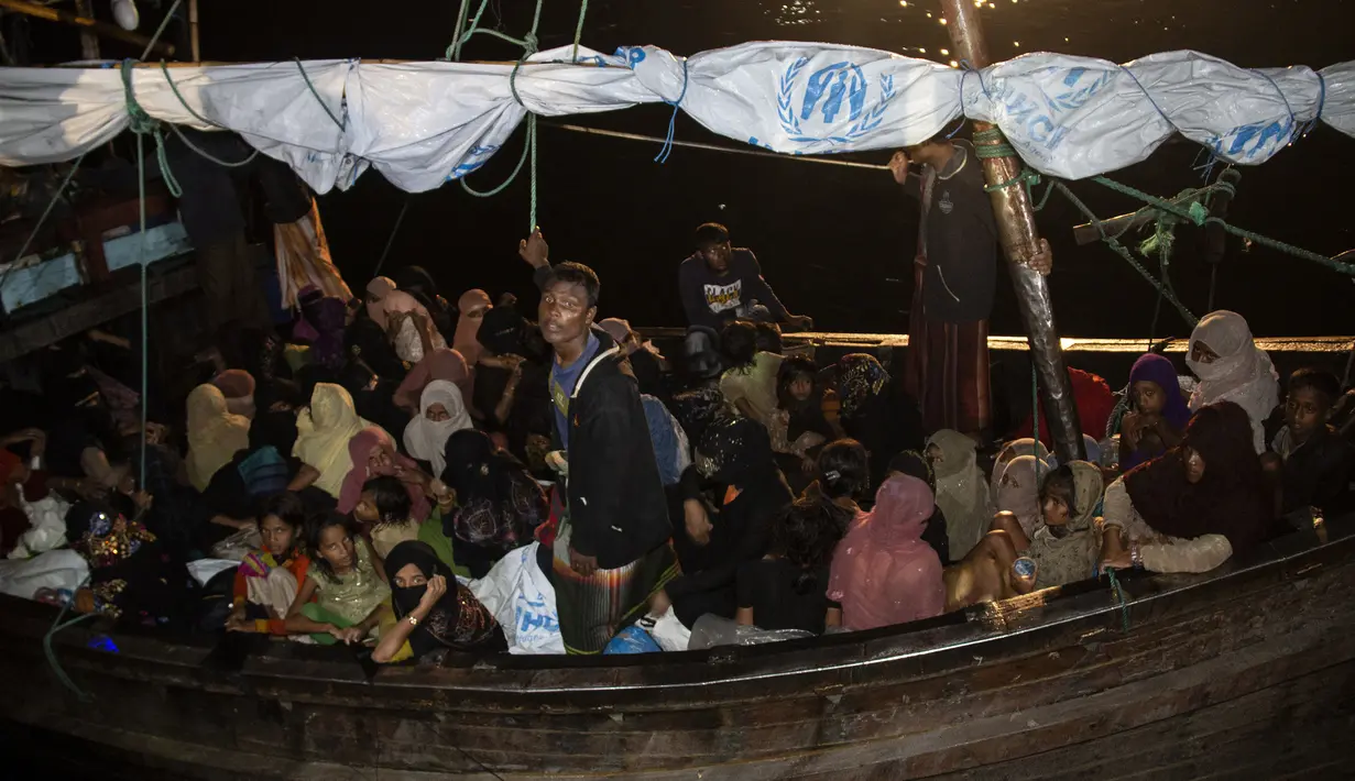 Pengungsi Rohingya duduk di perahu saat tiba di Pelabuhan Krueng Geukueh di Aceh Utara, Jumat pagi (31/12/2021). Para pengungsi yang mayoritas perempuan dan anak-anak tersebut dalam kondisi lemas dan kedinginan, karena diguyur hujan. (AP Photo/Zik Maulana)
