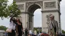 Orang-orang berswafoto dengan latar belakang Arc de Triomphe di jalan Champs Elysees, Paris, Kamis (17/6/2021). Prancis mengumumkan melonggarkan aturan pembatasan COVID-19, mencabut aturan penggunaan masker di luar ruangan dan menghentikan jam malam mulai pekan ini. (AP Photo/Michel Euler)