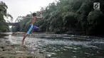 Seorang anak melompat ke Sungai Ciliwung, Depok, Jawa Barat, Kamis (4/7/2019). Menurunnya debit air Sungai Ciliwung akibat musim kemarau dimanfaatkan warga setempat sebagai tempat wisata gratis untuk mengajak anak berenang. (merdeka.com/Iqbal Nugroho)