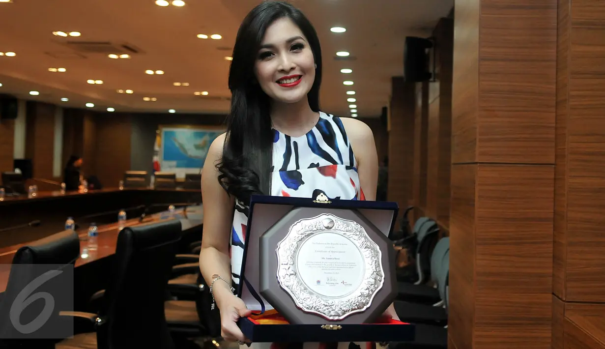 Sandra Dewi berpose dengan penghargaannya usai acara ramah tamah Dubes Korea bersama Jurnalis di Jakarta, Kamis (10/12). Penghargaan yang diberikan ini atas partisipasi Sandra Dewi dalam memperkenalkan Budaya Korea di Indonesia. (Liputan6.com/Johan Tallo)