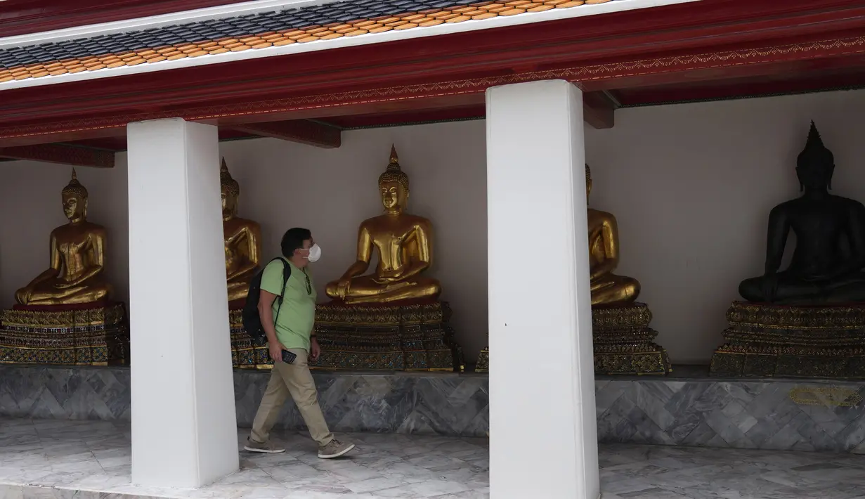 Turis yang mengenakan masker berjalan-jalan di kuil Wat Pho di Bangkok, Thailand, pada 23 Februari 2022. Thailand akan melonggarkan beberapa persyaratan masuk bagi turis asing untuk membangun kembali yang rusak akibat pandemi ekonomi mulai 1 Maret mendatang. (AP Photo/Sakchai Lalit)