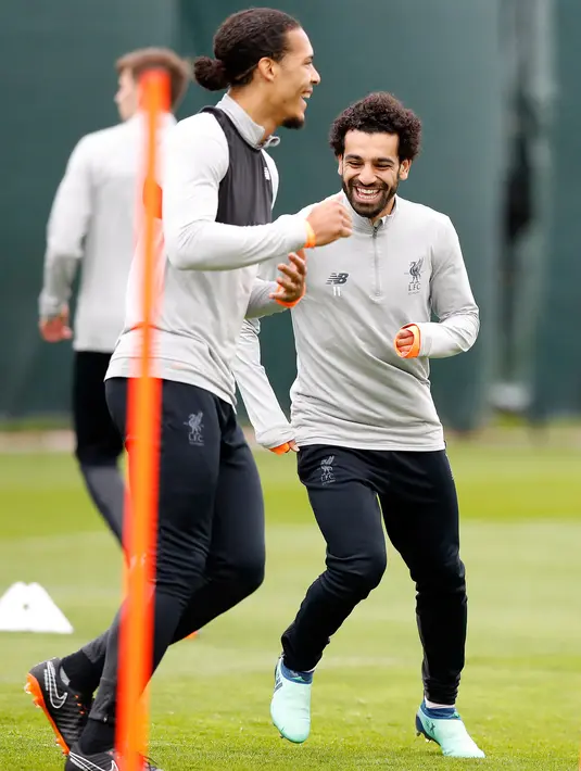 Penyerang Liverpool Mohamed Salah (kanan) tertawa bersama bek Virgil van Dijk saat mengikuti sesi latihan jelang menghadapi AS Roma di kompleks pelatihan Melwood tim di Liverpool, Inggris barat laut, (23/4). (AP Photo/Martin Rickett)