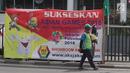 Pedagang melintas dekat bendera negara peserta Asian Games 2018 yang diikat di tiang bambu di pagar pembatas Jalan Pluit Selatan Raya, Jakarta, Kamis (19/7). Pemasangan merupakan inisiatif warga dalam memeriahkan Asian Games. (Liputan6.com/Arya Manggala)