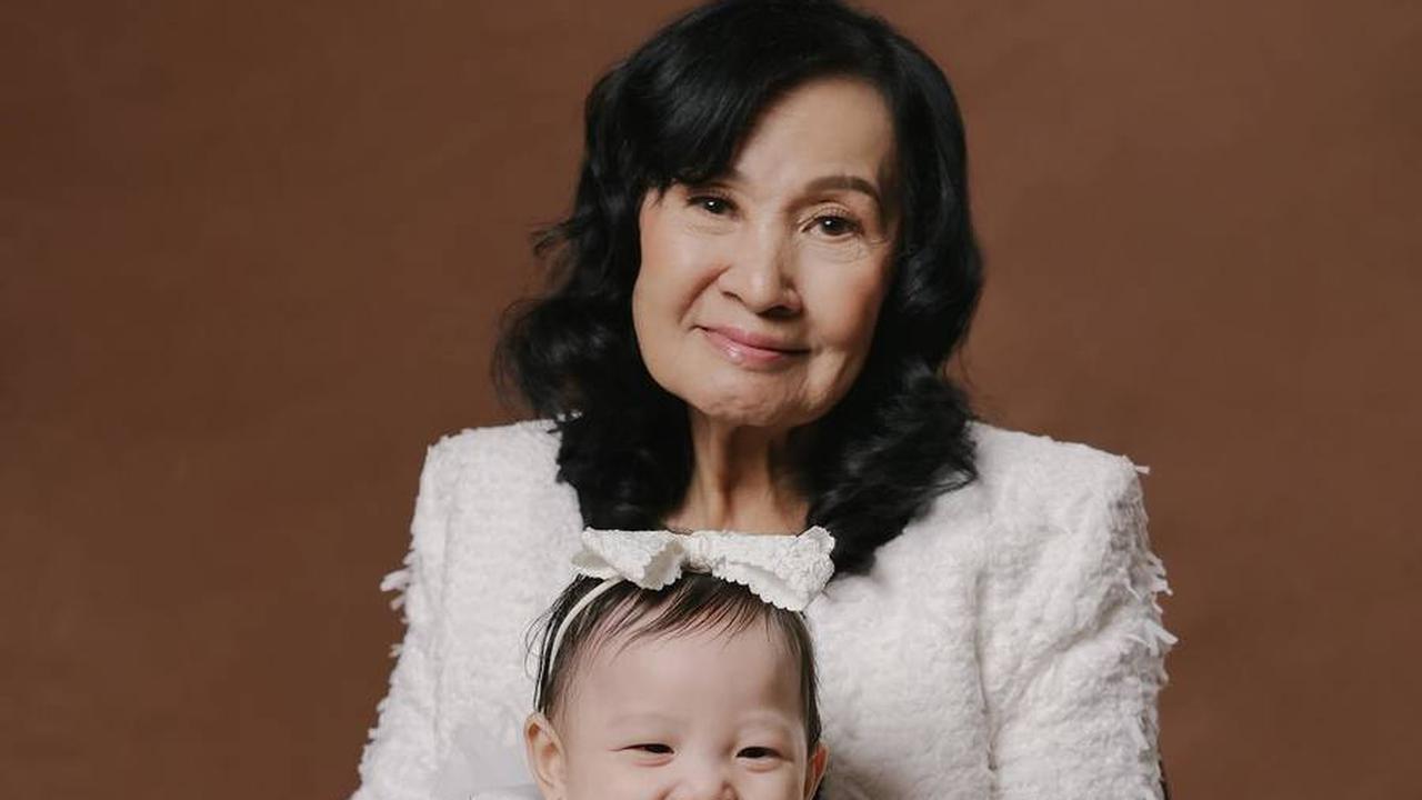 Tidak hanya sadar kamera, bayi cantik yang satu ini juga memamerkan senyuman lebarnya saat digendong oleh nenek buyutnya.