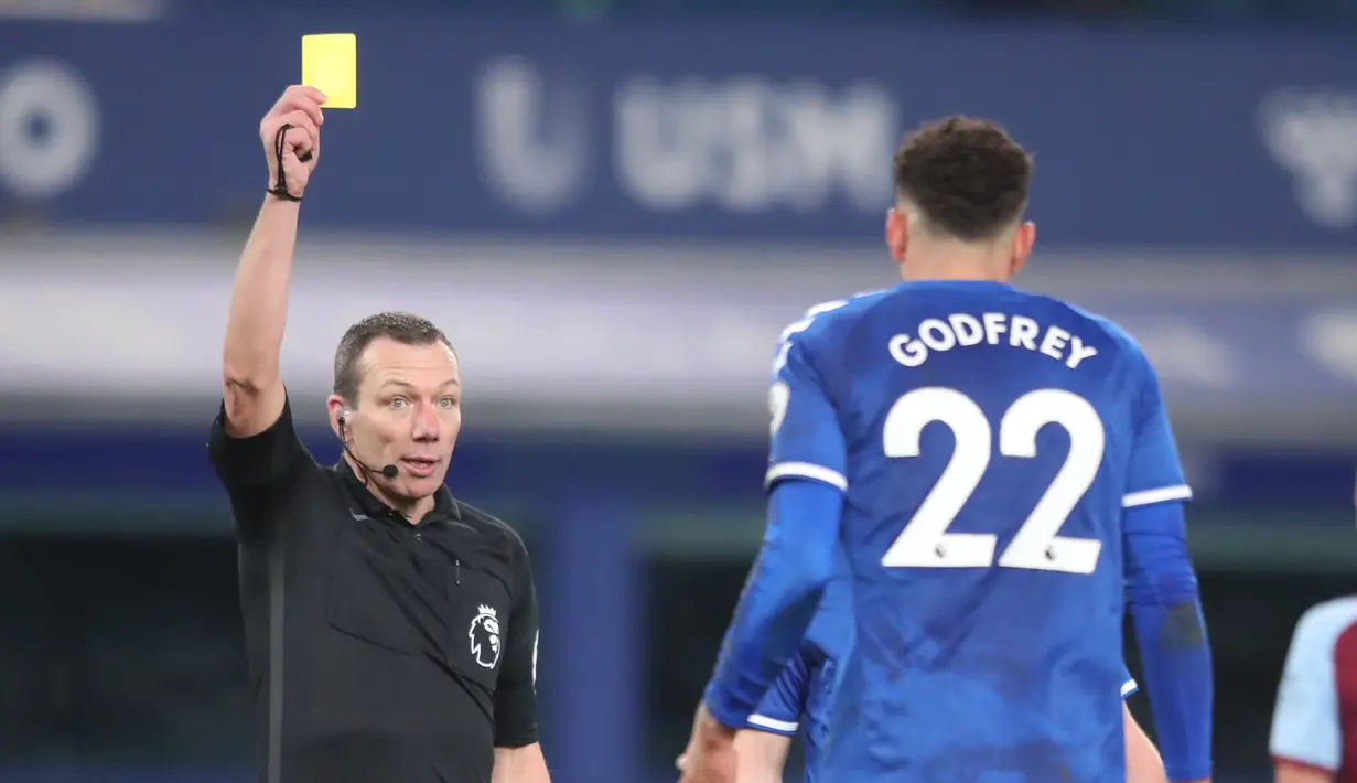 Wasit Kevin Friend (kiri) memberi kartu kuning kepada gelandang Everton, Ben Godfrey dalam laga lanjutan Liga Inggris 2020/21 pekan ke-17 melawan West Ham United di Goodison Park, Jumat (1/1/2021). Everton kalah 0-1 dari West Ham United. (AFP/Alex Pantling/Pool)