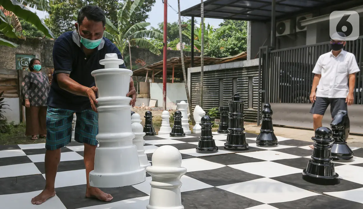 Warga bermain catur raksasa sambil menunggu waktu berbuka puasa di Pondok Betung, Tangerang Selatan, Kamis (14/5/2020). Tinggi bidak catur 50-86 cm dengan diameter sekitar 35 cm terbuat dari bahan viber glass dengan luas lapangan 4,8m x 4,8m. (Liputan6.com/Fery Pradolo)