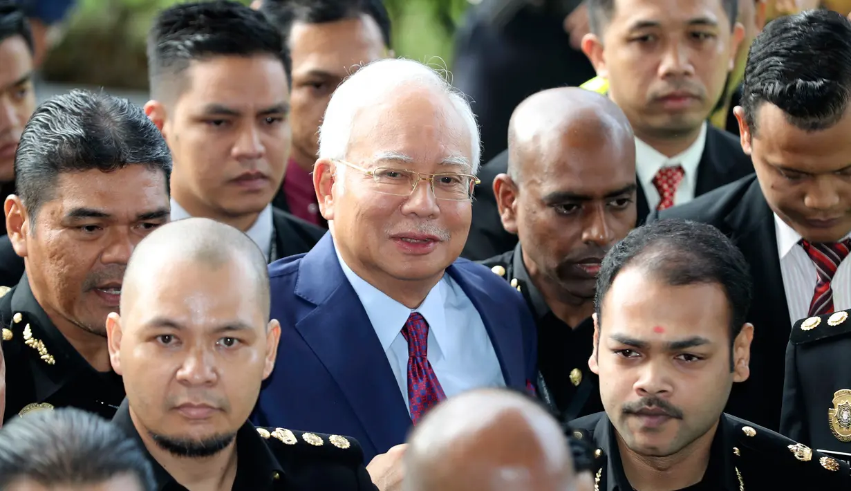 Mantan Perdana Menteri Malaysia, Najib Razak tiba untuk menjalani sidang dakwaan di Pengadilan Kuala Lumpur, Rabu (4/7). Kerumunan media yang menunggu juga warga yang penasaran dengan kasus Najib berdesakan mengambil gambarnya. (AP/Vincent Thian)