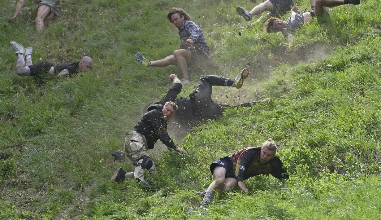 Cooper's Hill Cheese-Rolling and Wake adalah acara tahunan di mana para peserta berlomba menuruni bukit sepanjang 200 yard (180 meter) sambil mengejar roda keju Double Gloucester. (AP Photo/Kin Cheung)