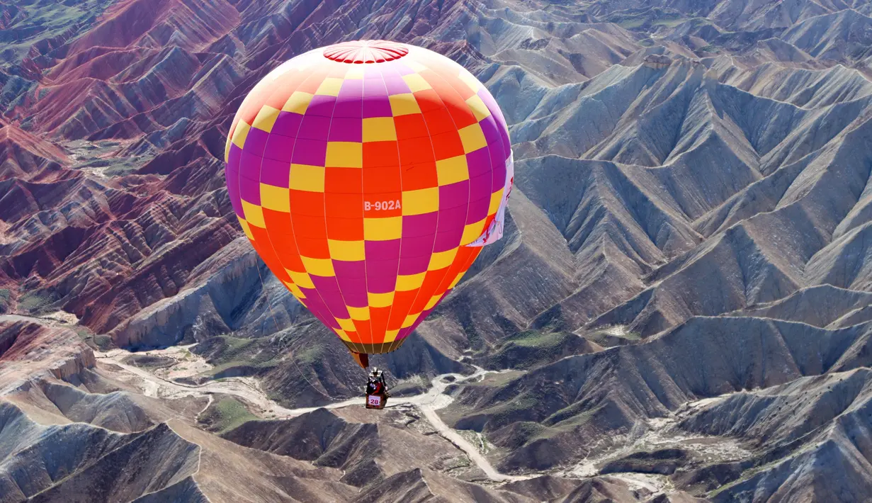 Sebuah balon udara terbang di langit Taman Geologi Nasional Danxia di Zhangye, Provinsi Gansu, China barat laut, pada 26 Juli 2020. Sebuah festival balon udara internasional dibuka di Zhangye pada Minggu (26/7). Total 100 balon udara akan ditampilkan dalam festival tersebut. (Xinhua/Cheng Lin)