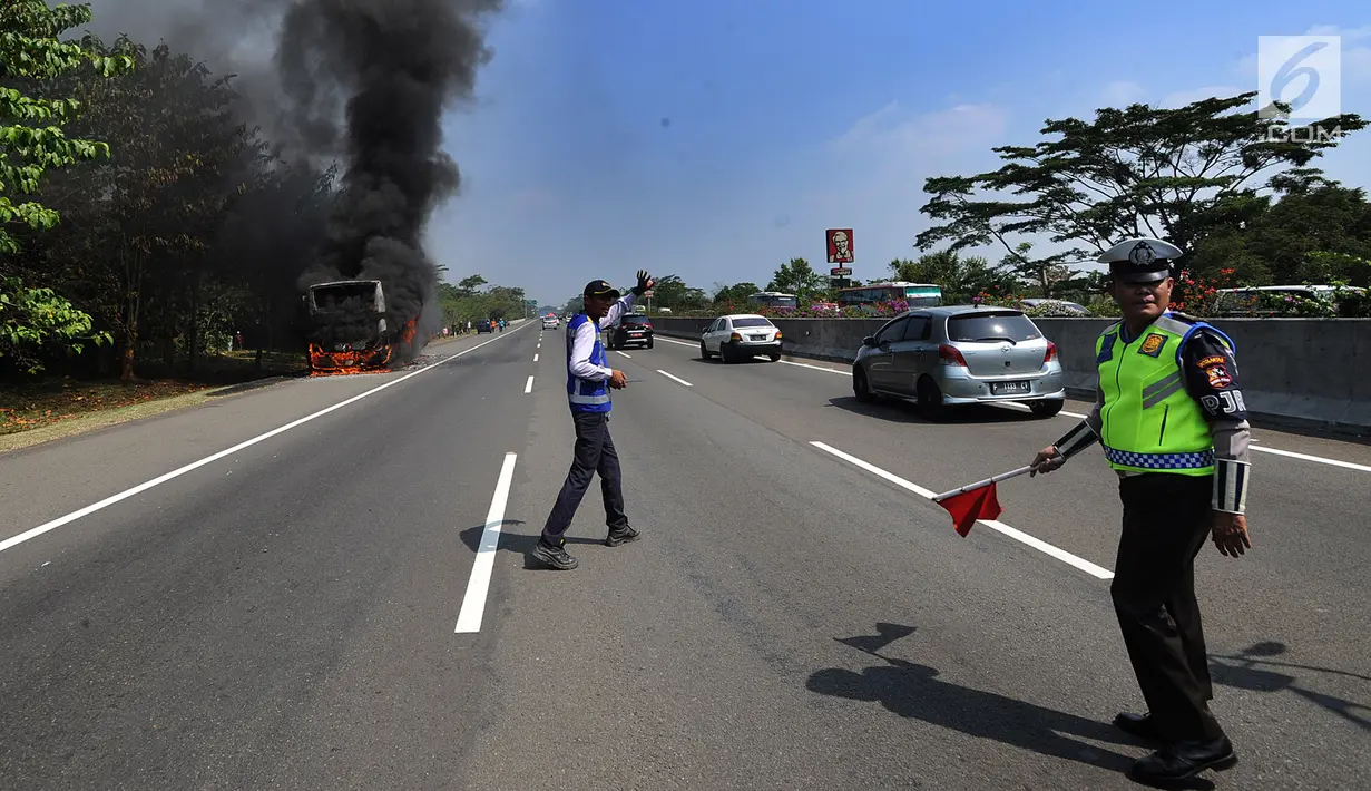 Petugas mengatur lalu lintas saat bus pariwisata nopol AB 7536 AK terbakar pada ruas tol Jagorawi arah Bogor di KM 36, Bogor, kamis (25/7/2019). Bus kosong yang diawaki dua orang ini terbakar habis dengan api yang bersumber pada bagian AC bus. (merdeka.com/Arie Basuki)