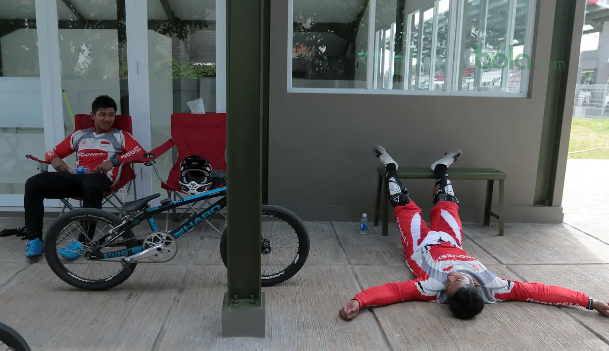 Atlet BMX, Rio Akbar (kiri) dan Toni Syarifudin beristirahat sejenak usai berlaga di Track BMX Pulomas, Jakarta (21/6/2018). Tiga atlet BMX putra Indonesia bersaing mengikuti seleksi menuju Asian Games 2018. (Bola.com/Nick Hanoatubun)