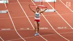 Pelari Indonesia, Nova Emilia membawa bendera merah putih usai finis di urutan kedua setelah pelari Korea Selatan Jung Hyelim pada final atletik nomor lari halang rintang 100 meter putri di Stadion Utama GBK, Jakarta (26/8). (Liputan6.com/Fery Pradolo)