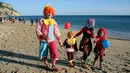 Sebuah keluarga mengenakan kostum badut berjalan di pantai saat mengikuti Parade Karnaval Clowns di pantai Sesimbra, Lisbon, Spanyol (12/2). Karnaval ini digelar setiap tahun dan jatuh pada hari Senin. (AP Photo / Armando Franca)