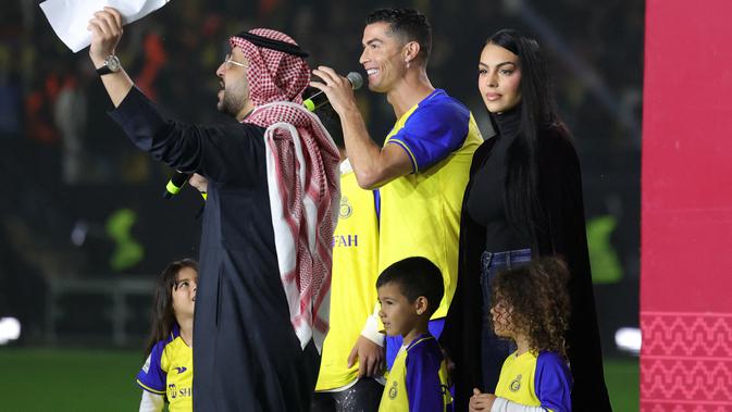 <p>Cristiano Ronaldo bersama sang kekasih Georgina Rodriguez dan anak-anaknya berdiri di atas panggung saat upacara penyambutan dirinya sebagai pemain baru Al Nassr di Stadion Mrsool Park, di ibu kota Saudi, Riyadh, Selasa (3/1/2023). Georgina Rodriquez seperti mengikuti kebudayaan di Arab Saudi dengan mengenakan pakaian yang lebih sopan dan tertutup. (Fayez Nureldine / AFP)</p>