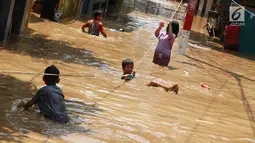 Anak-anak bermain saat banjir menggenangi kawasan Pejaten Timur, Jakarta, Jumat (26/4). Banjir yang berasal dari luapan Sungai Ciliwung tersebut merendam ratusan rumah warga hingga kedalaman lebih dari satu meter. (Liputan6.com/Immanuel Antonius)