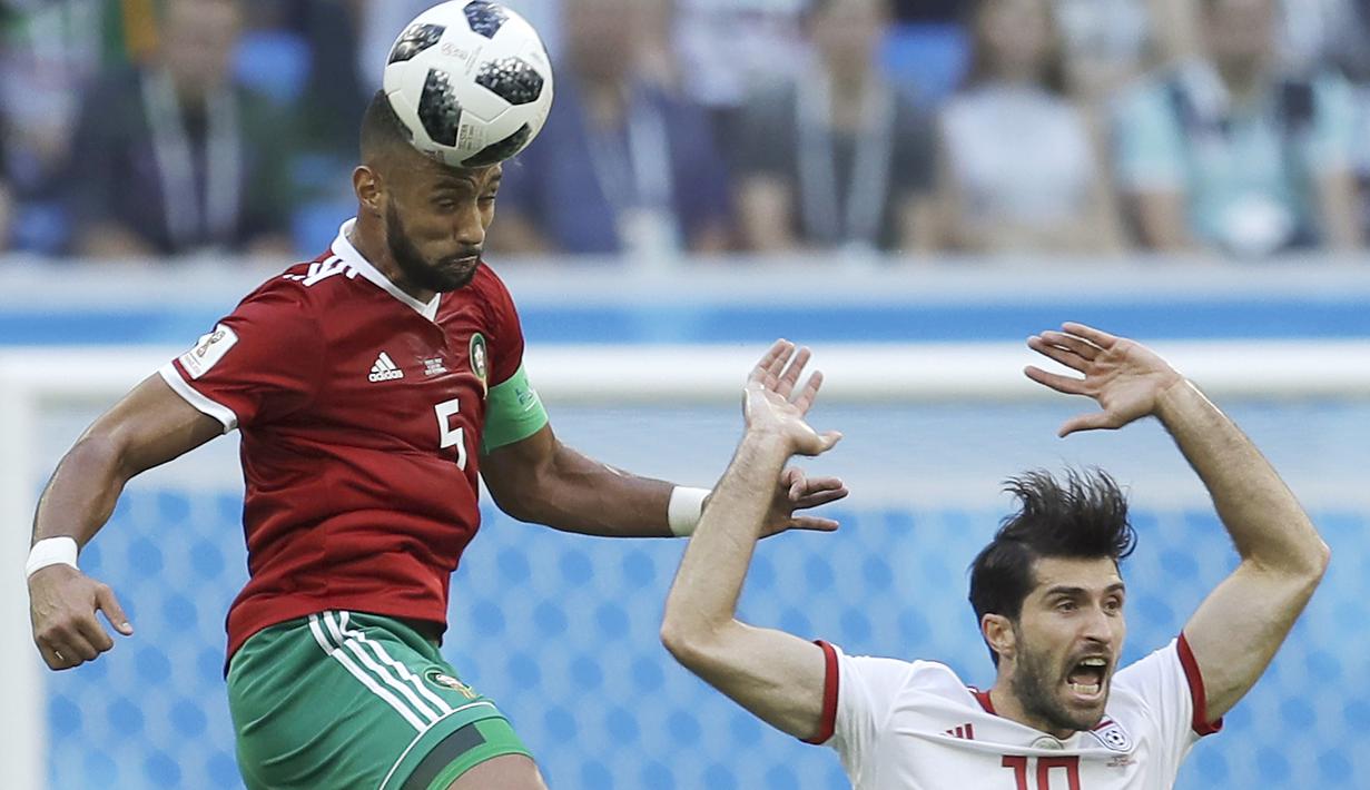Duel pemain Maroko, Mehdi Benatia (kiri) dan pemain Iran, Iran, Karim Ansarifard pada laga grup B Piala Dunia 2018 di St. Petersburg Stadium, Rusia, (15/6/2018). Iran menang 1-0. (AP/Themba Hadebe)