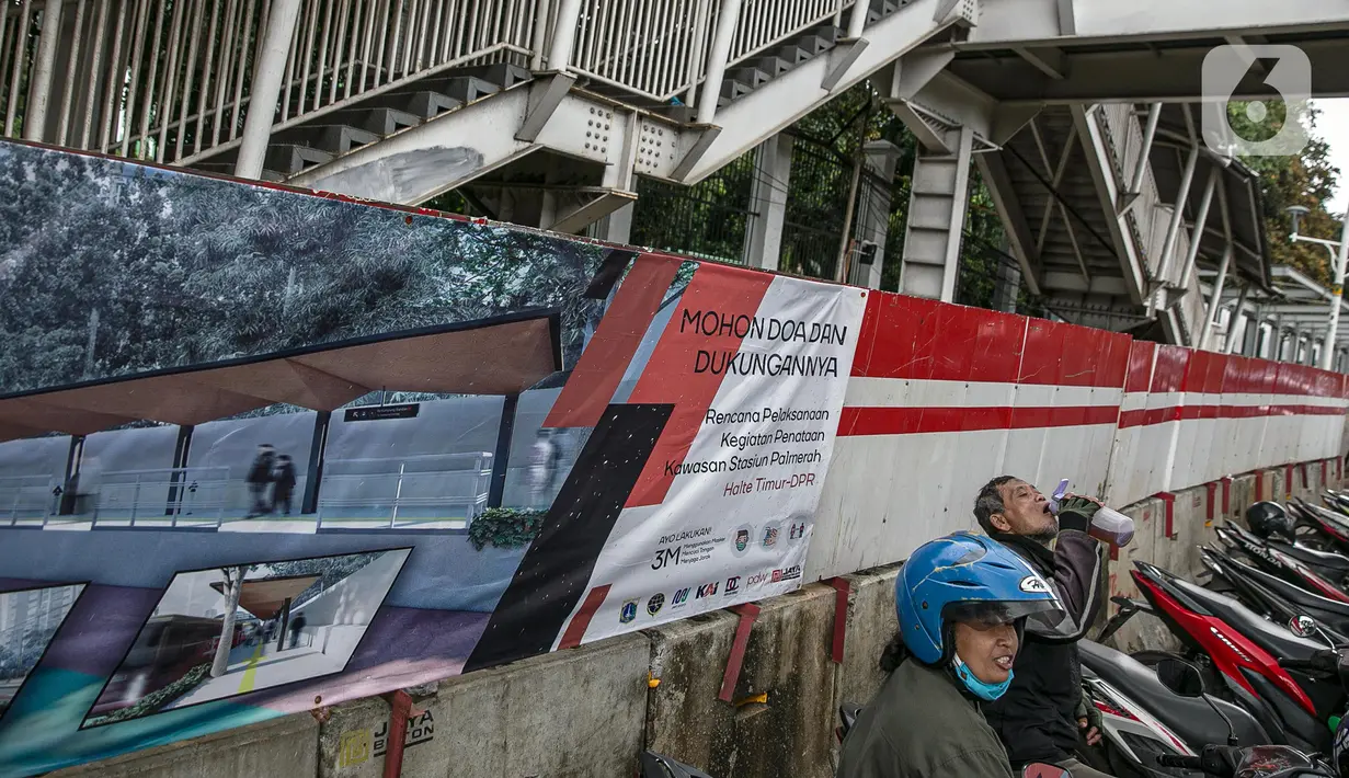 Warga beraktivitas di samping lokasi proyek pembangunan selter di kawasan Stasiun Palmerah, Jakarta, Selasa (2/2/2021). Penataan kawasan Stasiun Palmerah mencakup pembangunan selter untuk bus, angkot, dan ojek online. (Liputan6.com/Faizal Fanani)