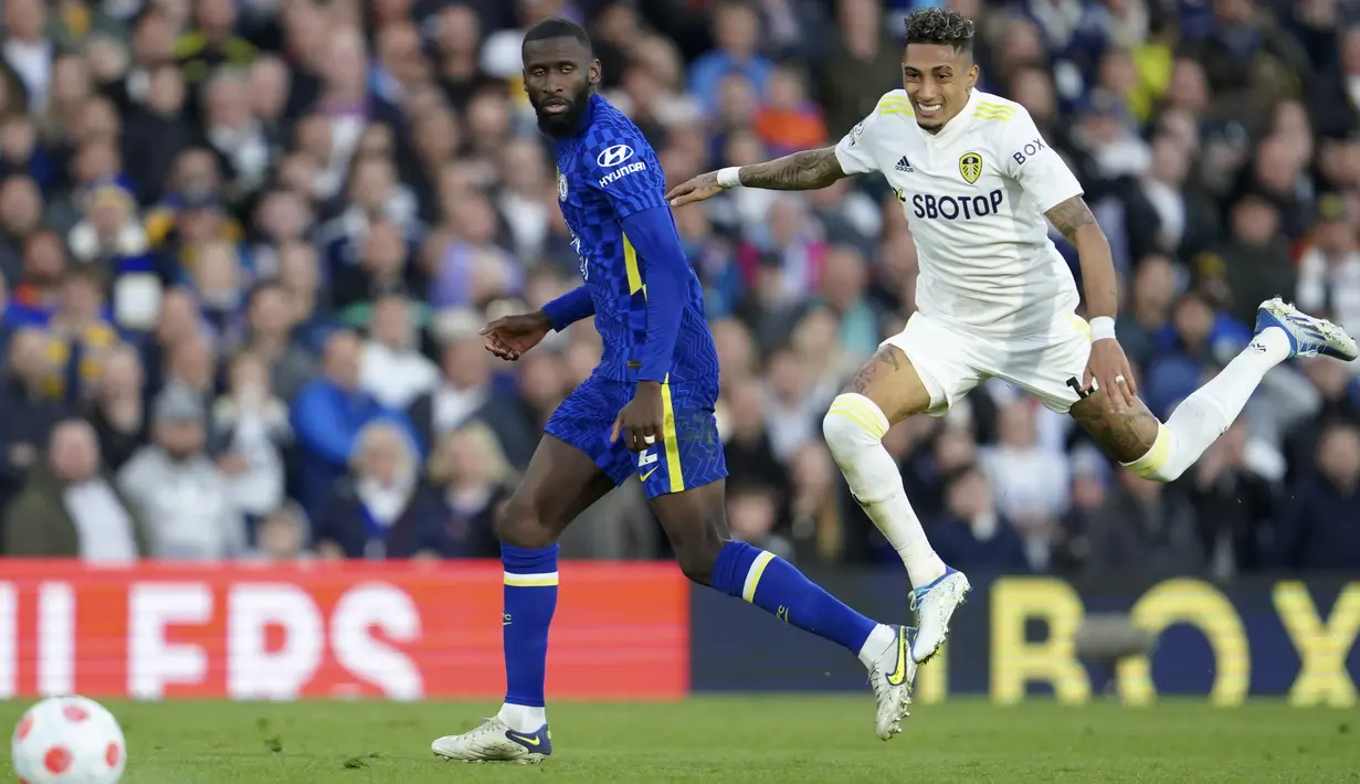 <p>Penyerang Leeds United Raphinha berebut bola dengan bek Chelsea Antonio Rudiger dalam laga tunda pekan ke-33 Liga Inggris 2021/2022 di Stadion Elland Road, Kamis (12/5/2022) dini hari WIB. Chelsea menang telak 3-0 atas Leeds United. (AP Photo/Jon Super)</p>