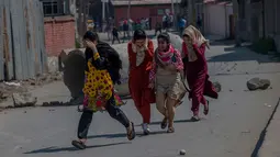 Sejumlah wanita Kashmir berusaha menyelamatkan diri saat terjadi bentrokan antara kelompok militan dan pasukan keamanan India di Shopian, Srinagar (4/1). Sering terjadi bentrokan antara kelompok separatis dan pasukan India. (AP Photo / Dar Yasin)