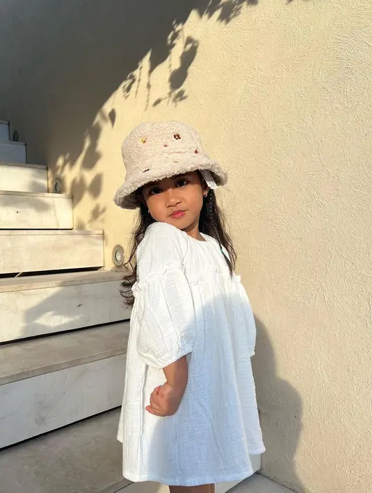Di lain foto kamu juga bisa menemukan potret Chava yang seakan-akan menirukan pose sang ibunda dengan dress putih dan topi lucunya ini. [Foto: IG/rachelvennya].