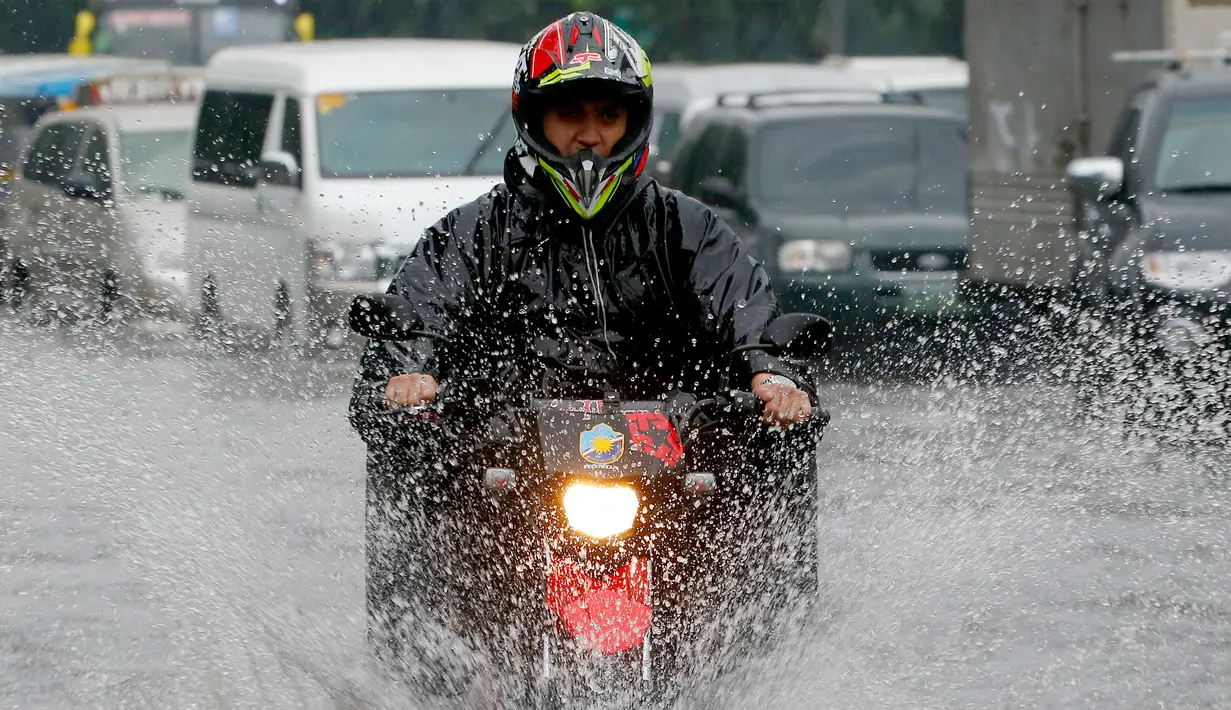 Pengendara sepeda motor menerjang genangan air akibat hujan lebat di Manila, Filipina, Kamis (27/7). Pihak Biro Cuaca setempat memberi peringatan agar warga terus berhati-hati beraktivitas di luar rumah selama musim penghujan. (AP/Bullit Marquez)
