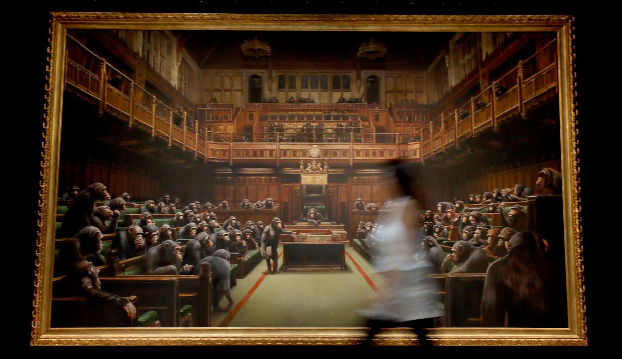 Petugas melintas di depan lukisan seniman jalanan Banksy yang dipajang di ruang lelang Sotheby, London, Jumat (27/9/2019). Lukisan tersebut pernah dipajang di pameran 'Banksy vs Bristol Museum' pada 2009 dan menarik lebih dari 300 ribu pengunjung. (AP/Kirsty Wigglesworth)