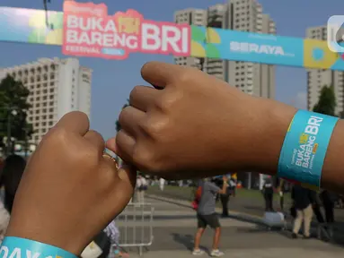 Pengunjung memperlihatkan gelang tangan KapanLagi Buka Bareng BRI Festival 2024 di Plaza Timur Senayan, Jakarta, Sabtu (23/3/2024). (Liputan6.com/Herman Zakharia)