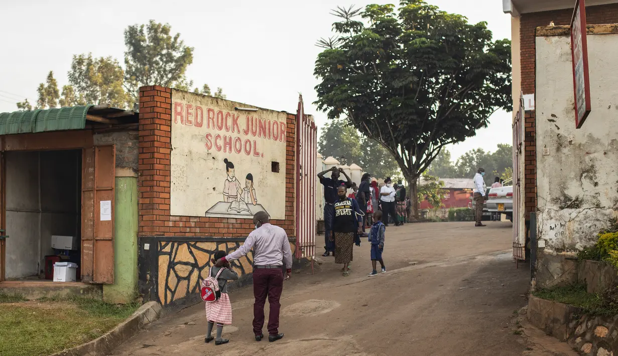 <p>Orang tua mengantar anaknya ke sekolah pada hari pertama pembukaan kembali setelah hampir dua tahun penutupan lembaga pendidikan di Kampala pada 10 Januari 2022. Sekolah-sekolah di Uganda dibuka kembali, mengakhiri penutupan sekolah terlama di dunia akibat pandemi COVID-19. (Badru KATUMBA/AFP)</p>