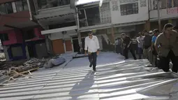 Presiden Ekuador, Rafael Correa berjalan di puing-puing bangunan yang hancur akibat gempa di Portoviejo, Ekuador, 18 April 2016. Dalam kesempatan tersebut, Rafael berbincang dengan warga yang menjadi korban gempa berkekuatan 7,8 SR. (REUTERS/Henry Romero)