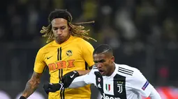 Bek Young Boys, Kevin Mbabu berebut bola dengan pemain Juventus, Douglas Costa pada laga pamungkas Grup H Liga Champions di Stade de Suisse, Kamis (13/12). Kalah 1-2, Juventus tetap keluar sebagai juara Grup H. (Fabrice COFFRINI/AFP)