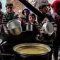 Anak-anak menunggu sambil memegang panci kosong bersama pengungsi Palestina lainnya untuk mendapatkan makanan menjelang berbuka puasa selama bulan suci Ramadhan, di Rafah di Jalur Gaza Selatan pada 16 Maret 2024. (SAID KHATIB/AFP)