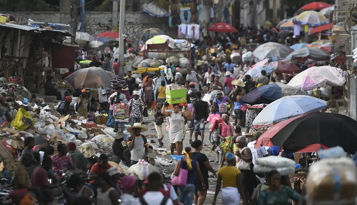 Seorang perempuan membawa baskom dengan barang-barangnya di pasar Petion-Ville di Port-au-Prince, empat hari setelah pembunuhan Presiden Haiti Jovenel Moise, Minggu (11/7/2021). Moïse tewas dibunuh dalam serangan di kediaman pribadinya, pada Rabu 7 Juli 2021 dini hari. (AP Photo/Matias Delacroix)